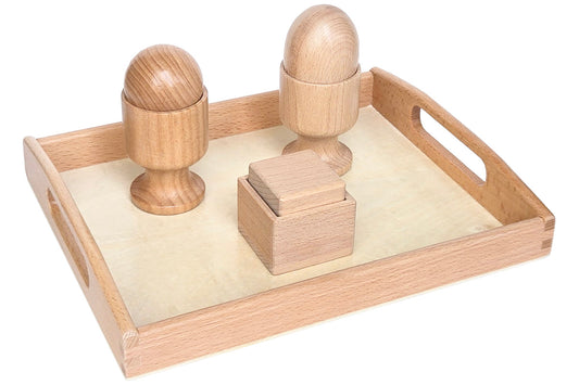 Wooden cube, sphere, and egg, each with a stand, all on a wooden tray.