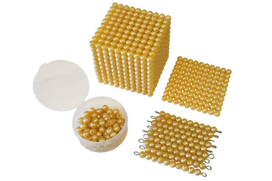 Golden bead materials: thousand cube, hundred square, ten bars, and unit beads in the old, lighter C bead colour.