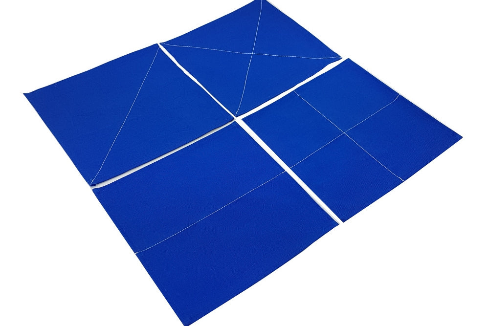 Four blue fabric squares with white stitches to fold along. Squares have a single diagonal, two diagonals, one horizontal, or both a horizontal and vertical fold.