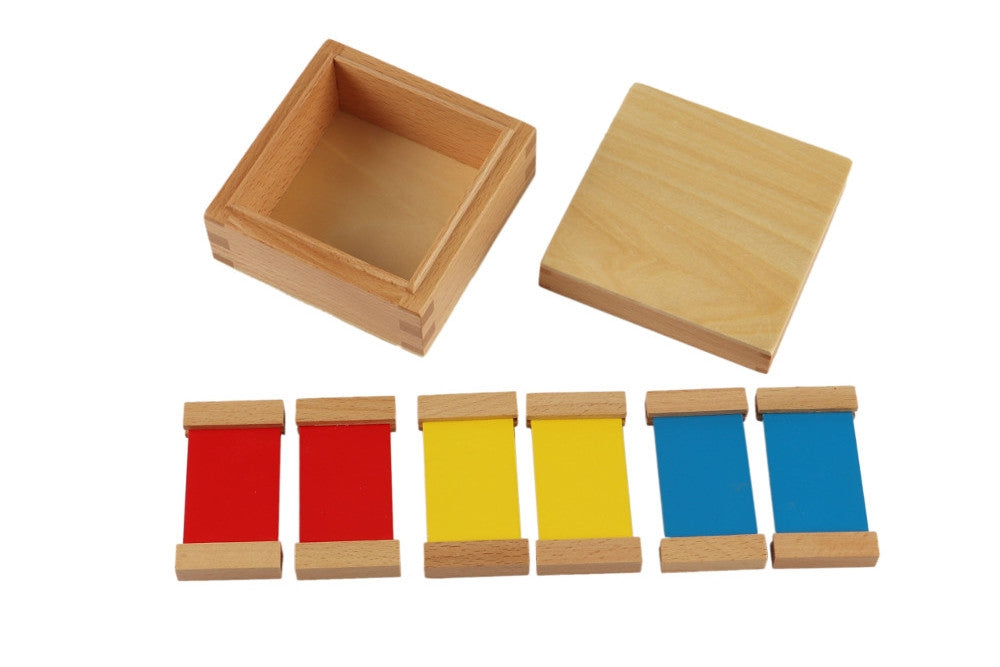 First colour tablet box. Small square box with a lid and three pairs of tablets in the primary colours red, yellow, and blue.