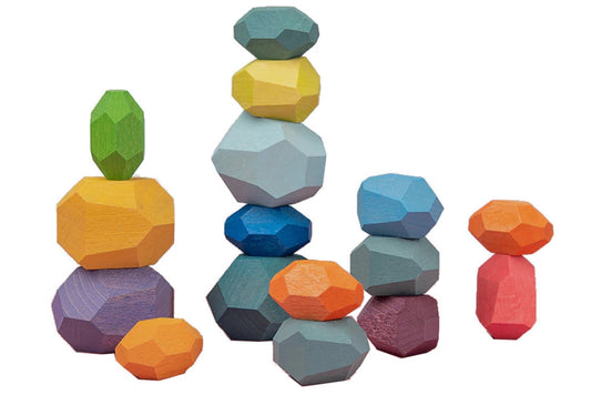 16 wood balancing stones in different colours, stacked into several pillars. Each "stone" has several faceted sides, like a gem.
