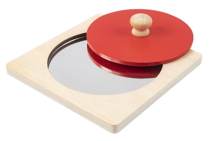 Red wooden circle puzzle with circular reflective surface on the base.