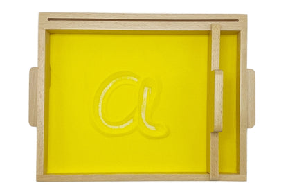 Sand tracing tray filled with yellow sand. The letter 'a' is traced into the sand.