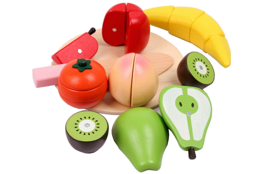 Wooden fruits laid on a circular cutting board with a knife.