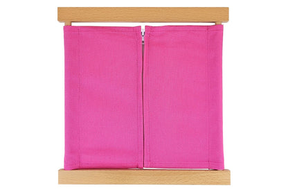 Wooden zipper dressing frame with pink fabric and white zipper.