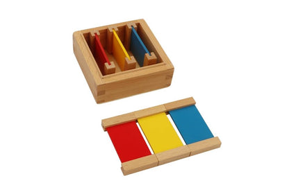 First colour tablet box. Small square box containing three pairs of tablets in the primary colours red, yellow, and blue. Three tablets are laid out in front of the box.