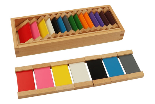 Second colour tablet box with one long rectangular compartment. Contains eleven pairs of tablets in the colours red, pink, yellow, white, black, blue, grey, green, orange, purple, and brown. Seven tablets are laid out in front of the box.